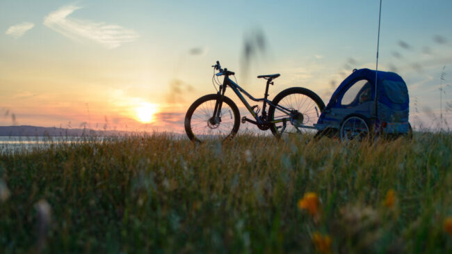 Photo of a bike with child trailer in the sunset. This can be a good way of getting out cycling when your child is little