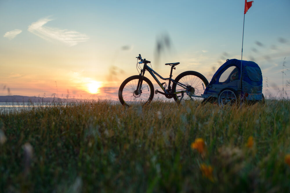 Photo of a bike with child trailer in the sunset. This can be a good way of getting out cycling when your child is little