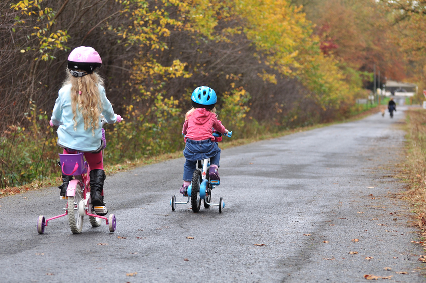 Girls riding on stabiliser bikes