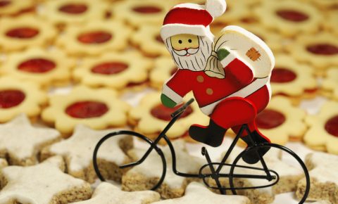 The best Christmas presents for kids who love to cycle - the image shows a little father christmas on a bike cycling through a plate of Christmas themed biscuits