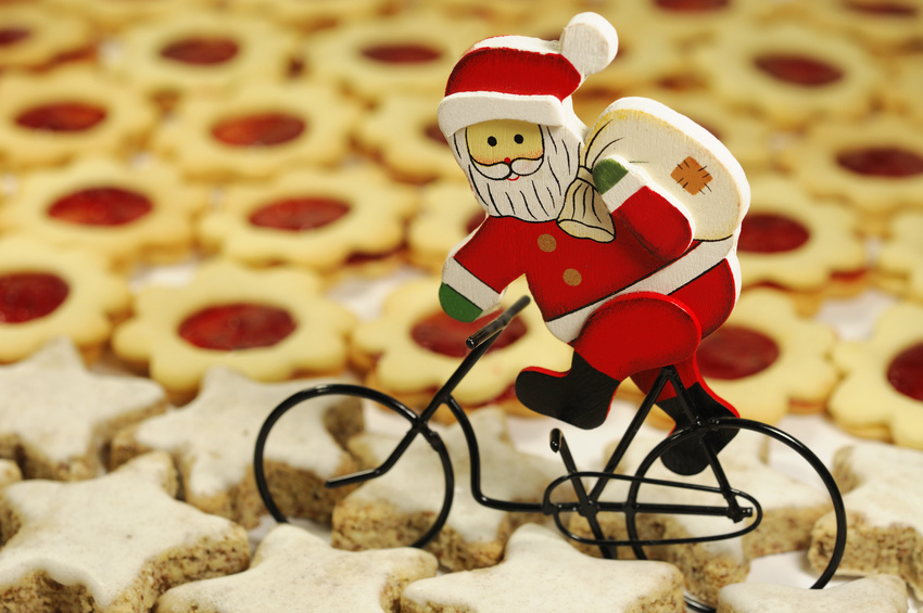 The best Christmas presents for kids who love to cycle - the image shows a little father christmas on a bike cycling through a plate of Christmas themed biscuits