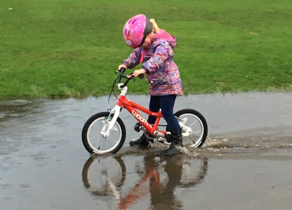 Best kids' bikes: A photo of our reviewer riding the woom bike through a puddle