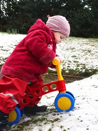 Can a toddler bike be used outside? This review finds out by putting the Lena My First Scooter to the test. Image shows it being used in the snow with the toddler riding it up a slope in their garden