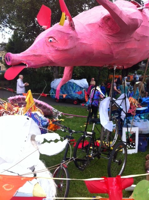 Paper mache flying pig attached to a tricycle at the Hebden Bridge Handmade parade