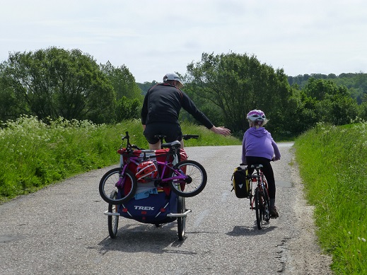 A cyclist towing a trailer with children's bikes tied to the back of it