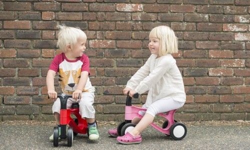 Two small toddlers riding toddlebikes outside together