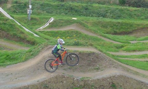 Practising front wheel lifts on an Islabikes Creig 24 at The Track Bike Park, Portreath, Redruth, Cornwall