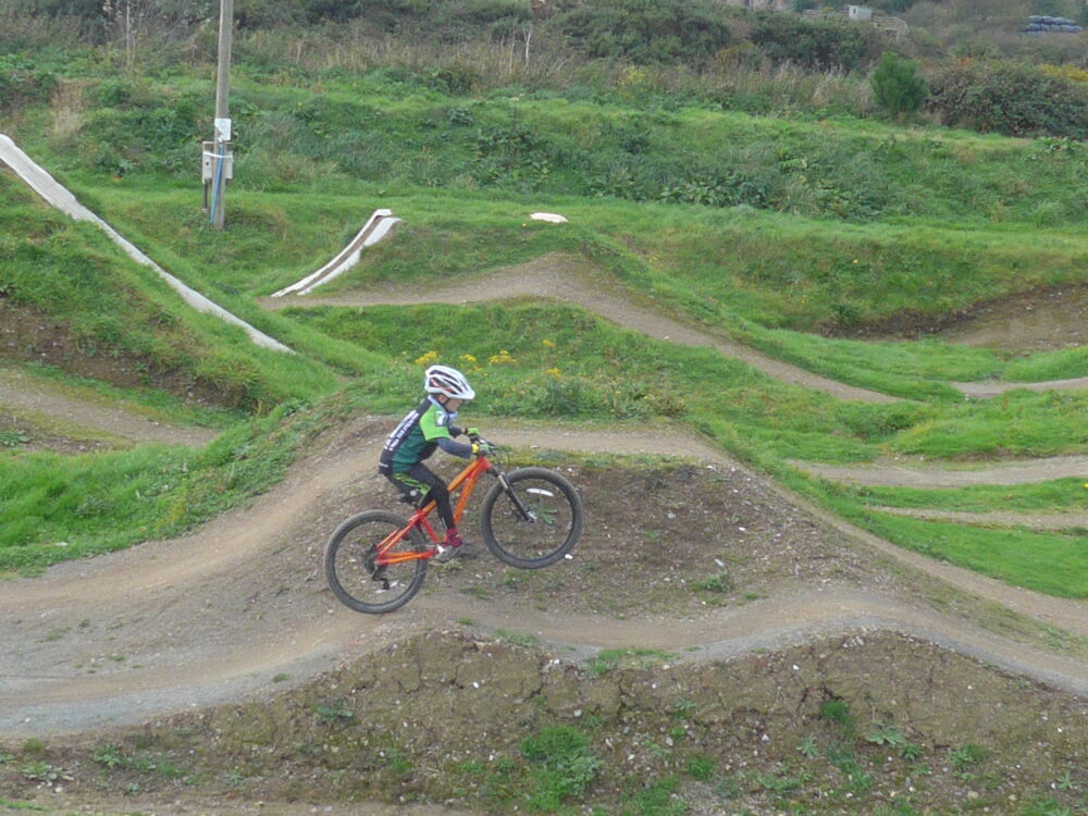 Practising front wheel lifts on an Islabikes Creig 24 at The Track Bike Park, Portreath, Redruth, Cornwall