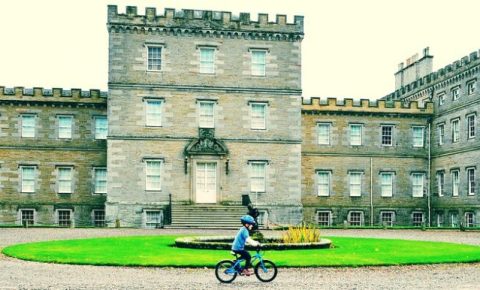 Young boy cycling in front of Mellerstain House