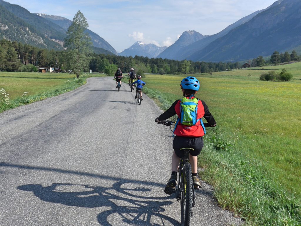 Family cycling in the Vallée de la Clarée in the French Alps - riding with the valley stretching out in front