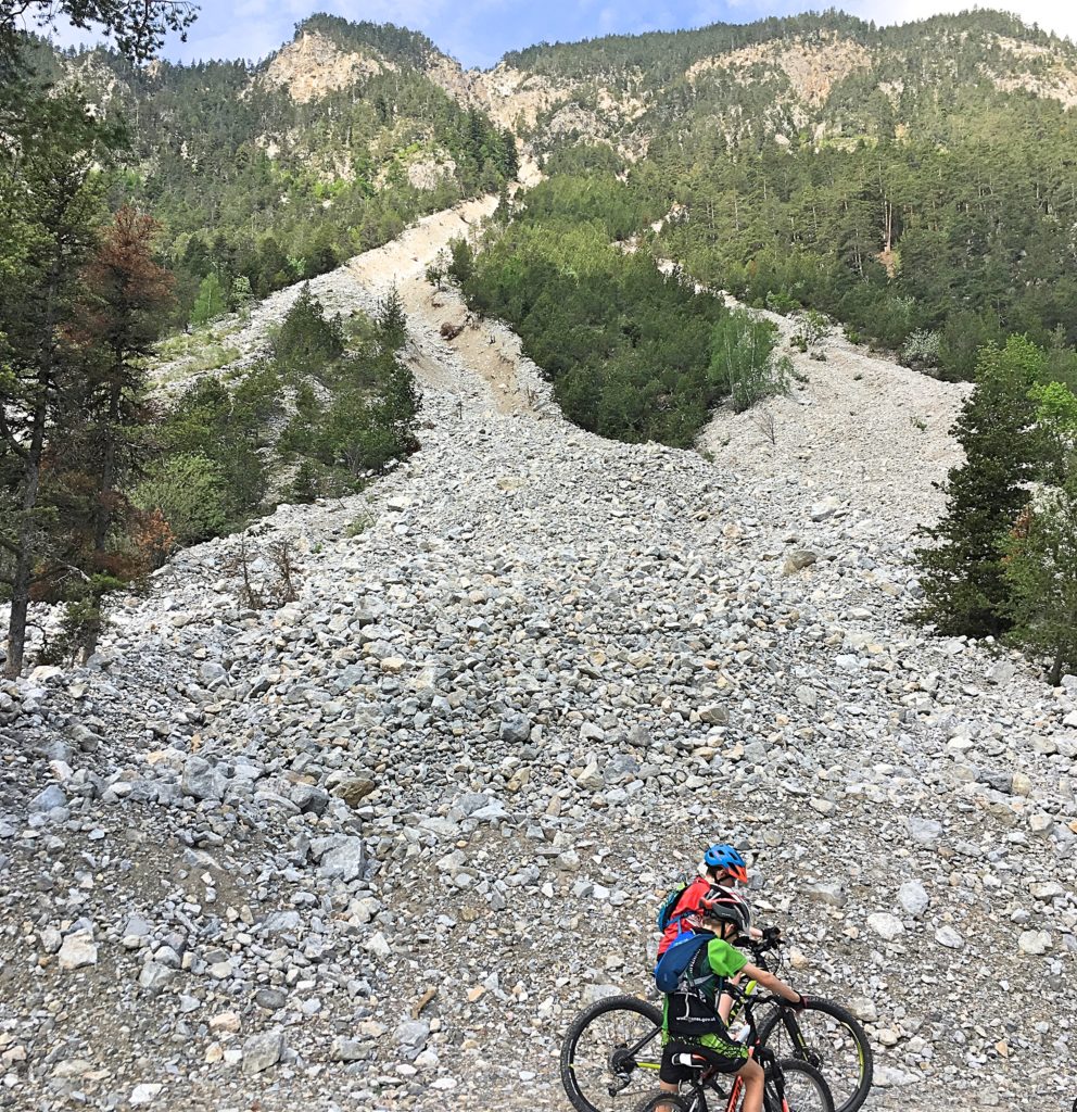 Family cycling in the Vallée de la Clarée in the French Alps - rock fall down towards river Claree close to Val-Des-Prés 