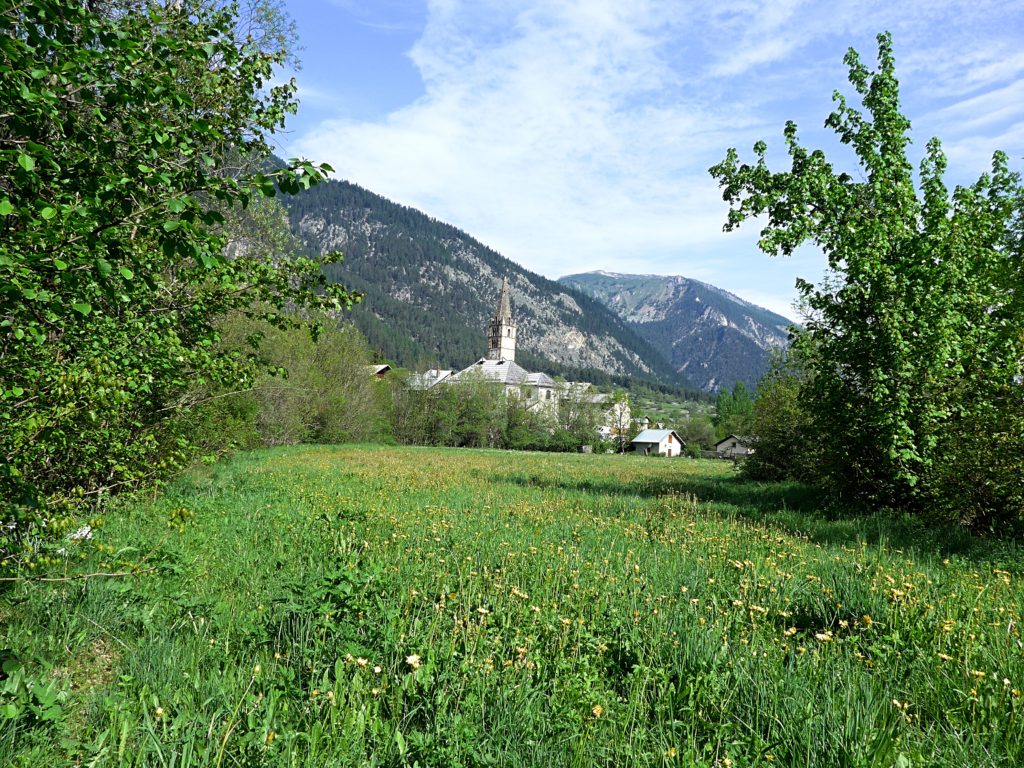 Family cycling in the Vallée de la Clarée in the French Alps - traditional village in the distance