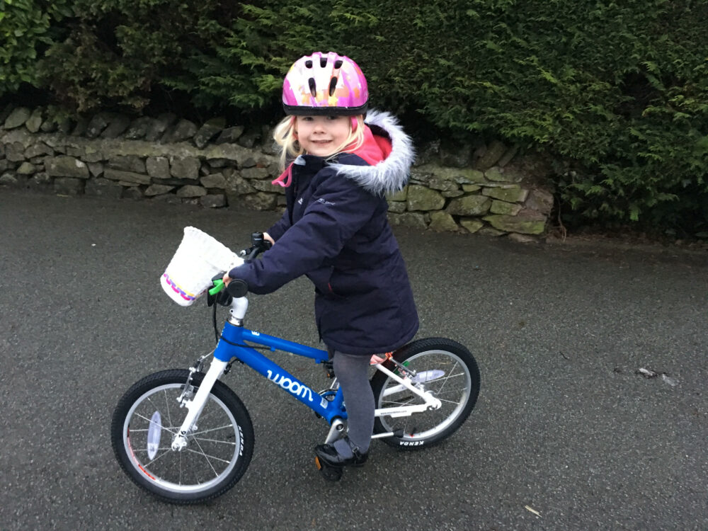 How to choose the right size kids' bike: A girl riding a Woom 3 on a quiet road