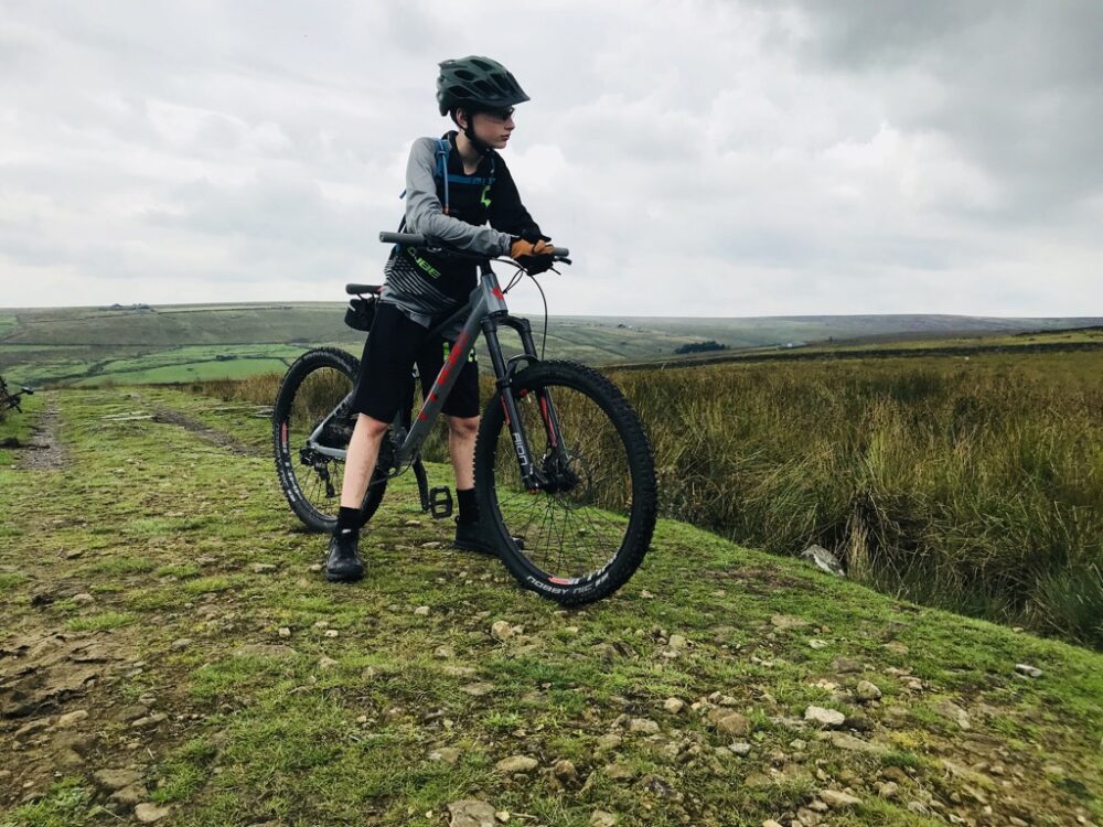 How to choose the right size kids' bike: A teenage boy on his bike on a grassy hill