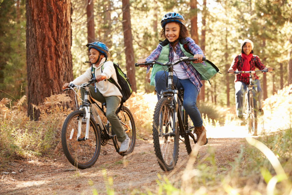 Two kids riding mountain bikes with an adult