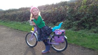 Girl on a bike with a dolls seat