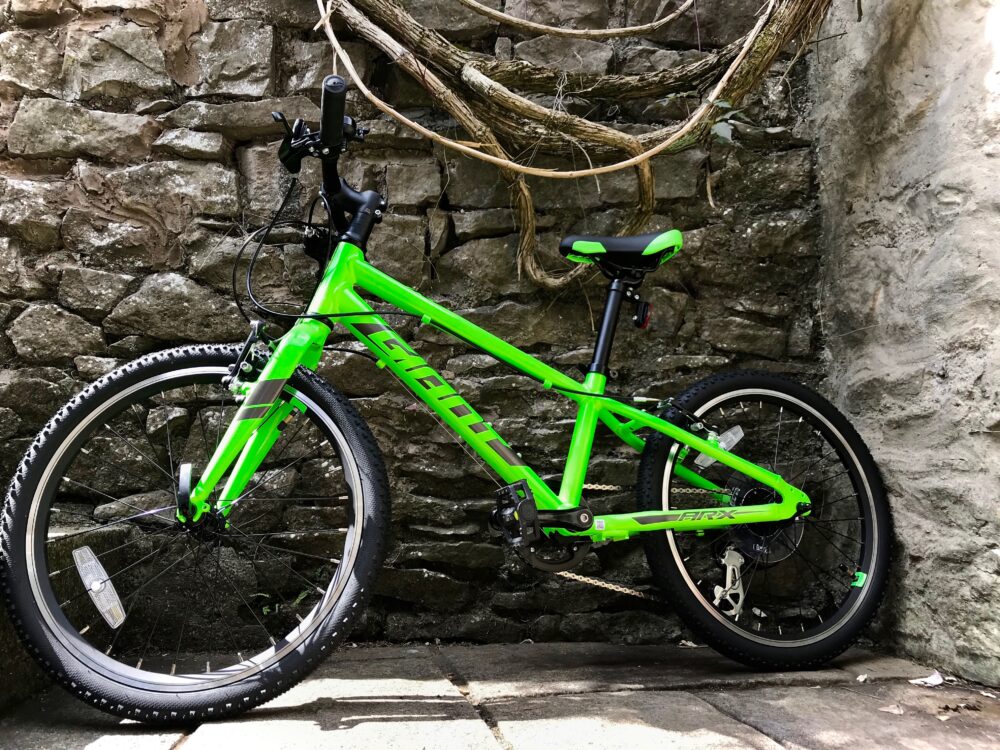 Best kids' bikes: A green Giant ARX bike in front of a brick wall