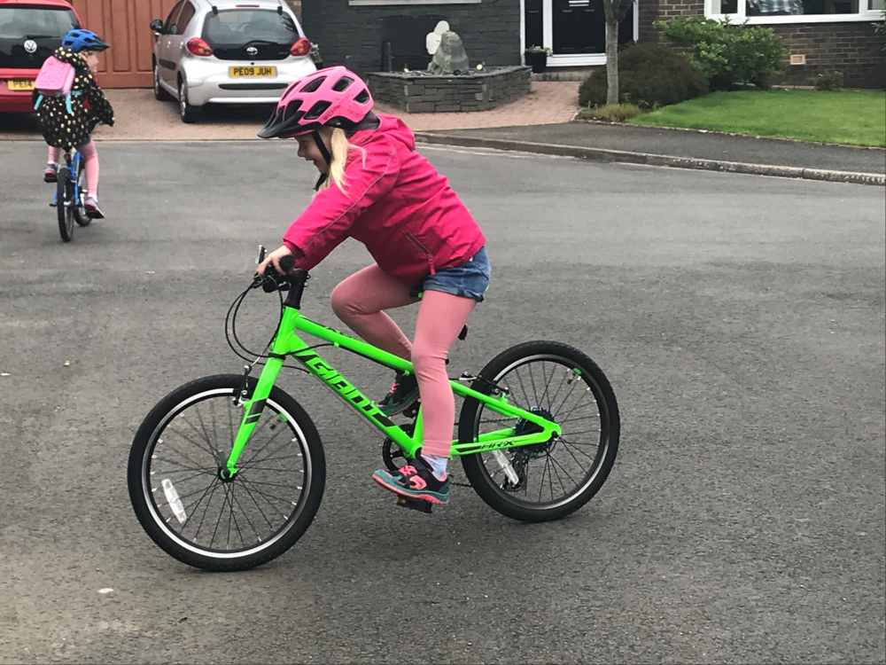How to choose the right size kids' bike: A girl riding on a Giant ARX on a quiet street