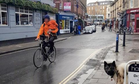 Man on bike holding child in Bristol