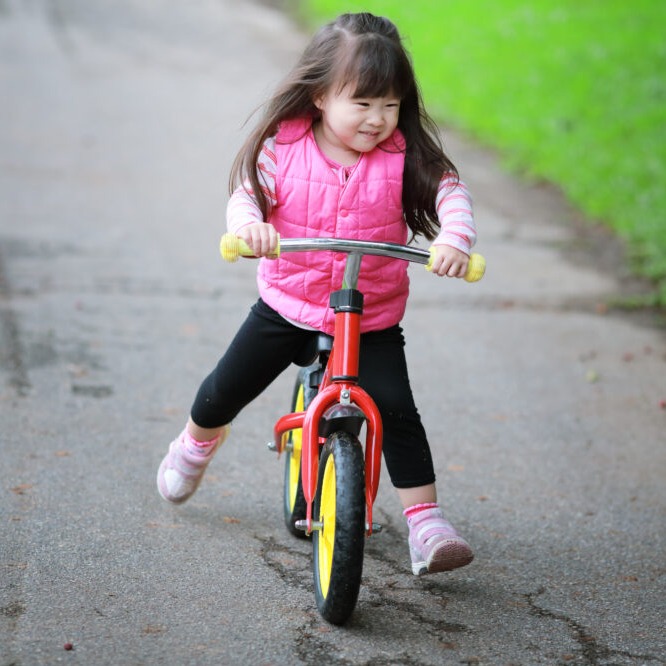 asian little girl on balance bike A balance bike in use showing why it's better than using stabilisers