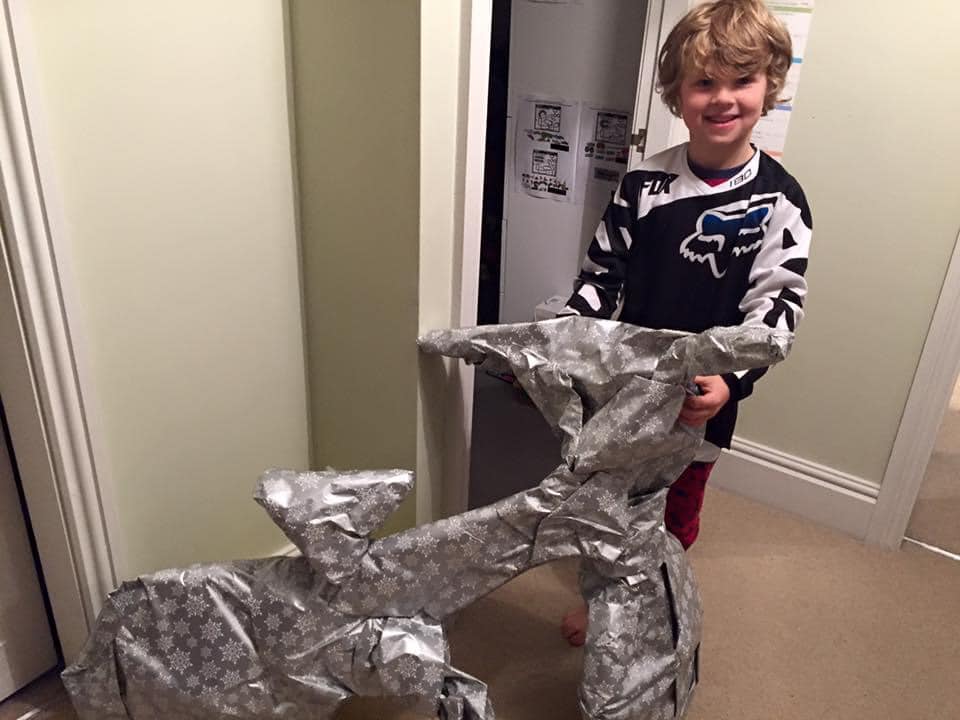 A cartoon of Father Christmas riding a bike with presents piled on the back