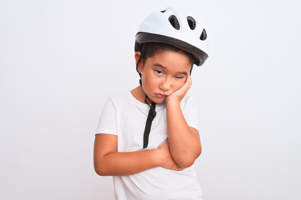 Boy wearing white cycling helmet not wanting to ride his bike