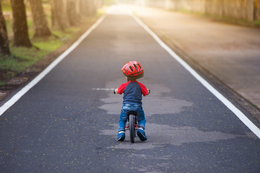 A little girl seen from behind wearing a blue MET bike helmet