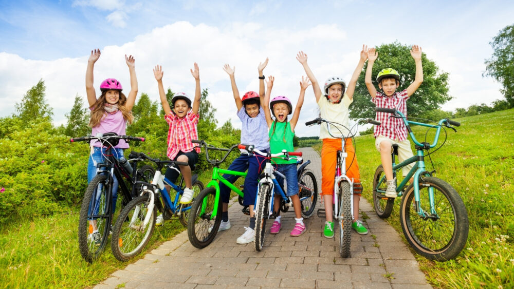 Big group of kids on bikes cheering (probably because their parents found them the best bike on the Cycle Sprog Search!)