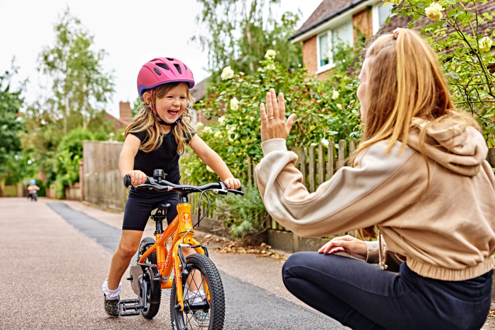 Photo of mum hi-fiving her young daughter who is riding a Forme Bike available to rent cheaply at The Bike Club