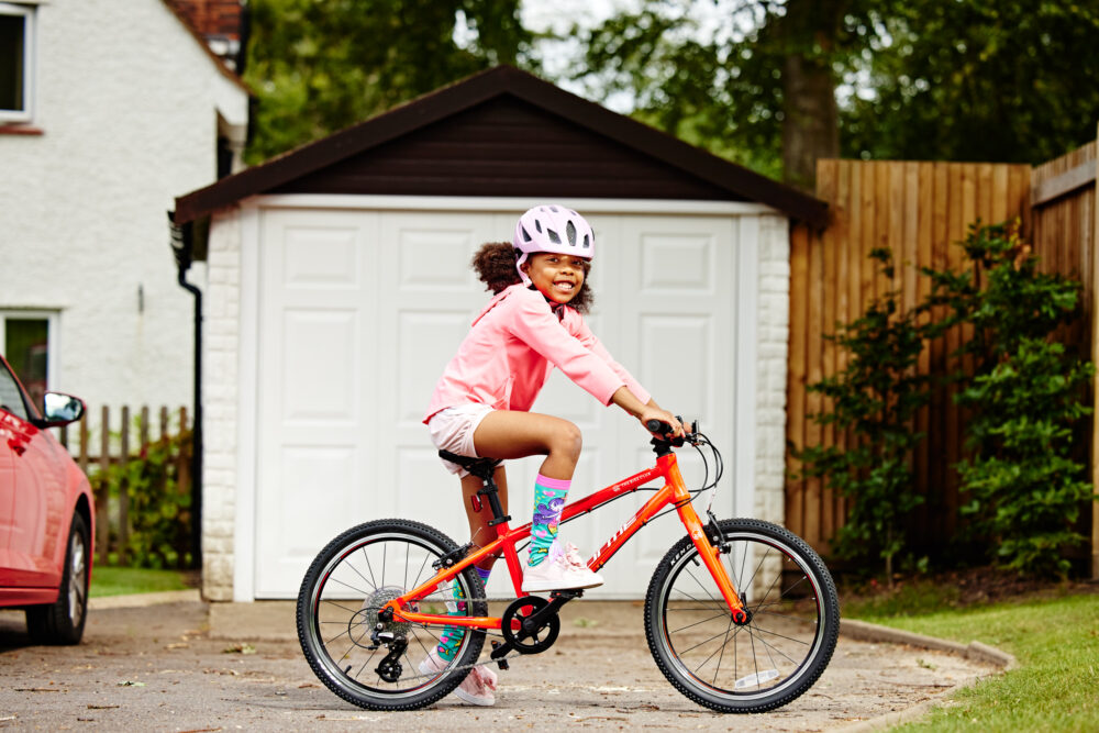 Photo of girl on red Forme bike outside her garage doors - Forme bikes are one of the quality kids bikes you can lease cheaply for your child from The Bike Club