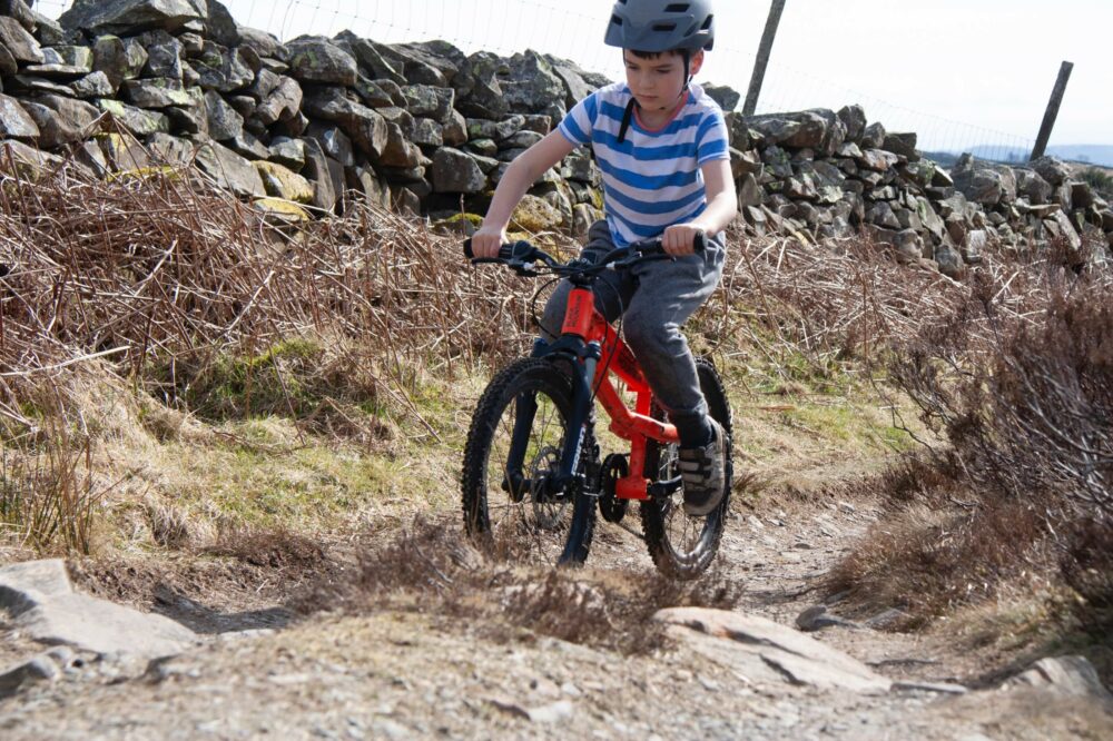 child riding black mountain bike with extending frame