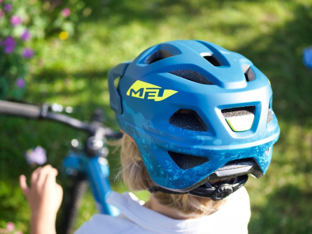 A little girl seen from behind wearing a blue MET bike helmet