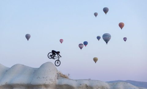 Kendal Mountain Festival Discount Code - SRPOG20 - Photo of cyclist jumping in mountains with lots of balloons in a clear sky