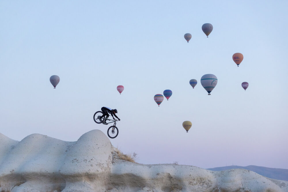 Kendal Mountain Festival Discount Code - SRPOG20 - Photo of cyclist jumping in mountains with lots of balloons in a clear sky