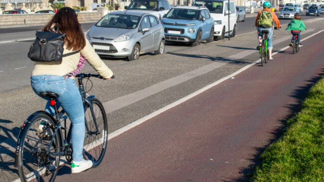 People cycling on a cycle path with a seperate footpath keeping both pedestrians and cyclists away from the vehicles driving on the road