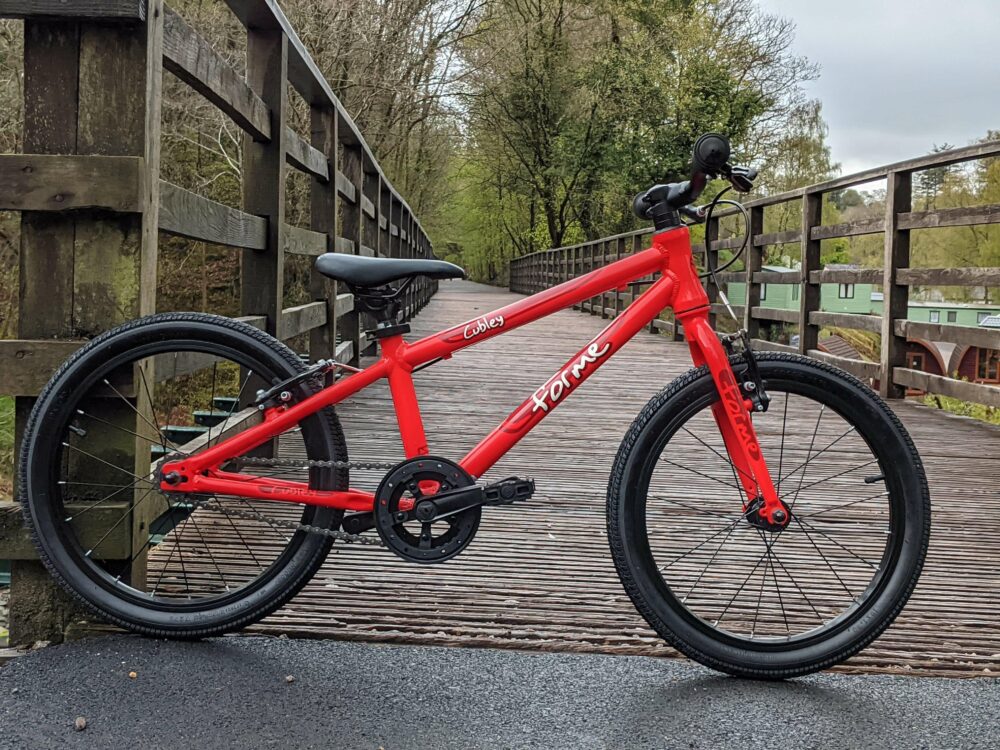 Photo of the red Forme Cubley 18 we were sent to review positioned on a pedestrian and cycling bridge over a river