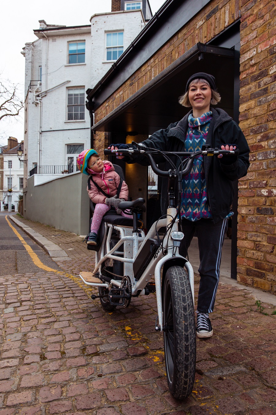 Mother and child in rear bike seat using the Mycle Electric Cargo Bike longtail Mycle cargo bike with mother and child