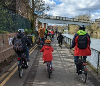 Kidical Mass - riders taking part riding in a long group next to a river