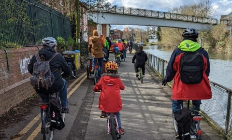 Kidical Mass - riders taking part riding in a long group next to a river