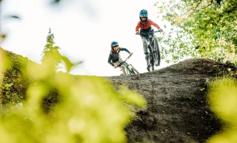 Best kids' full-suspension mountain bikes: Two kids riding full suspension mountain bikes in full face helmets.