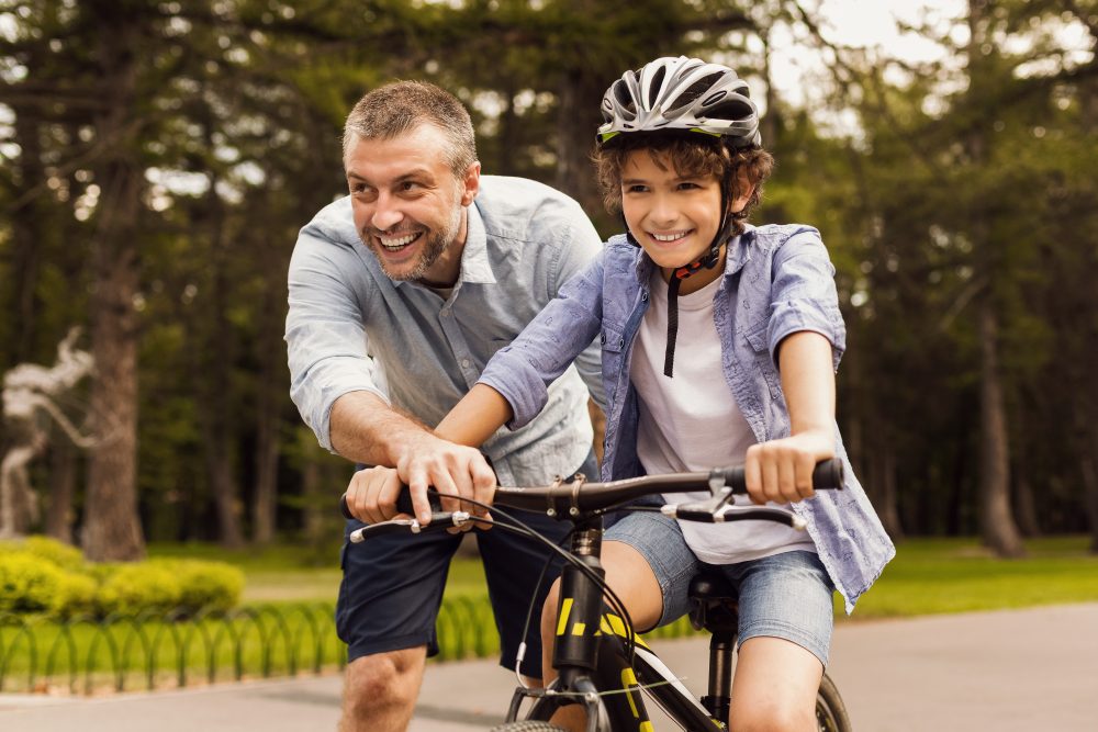 Dad teaching old child how to ride a bike