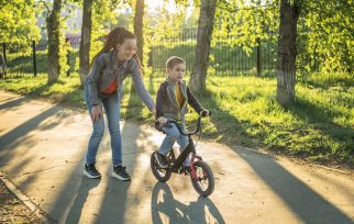 Mum teaching boy to ride a bike in a park