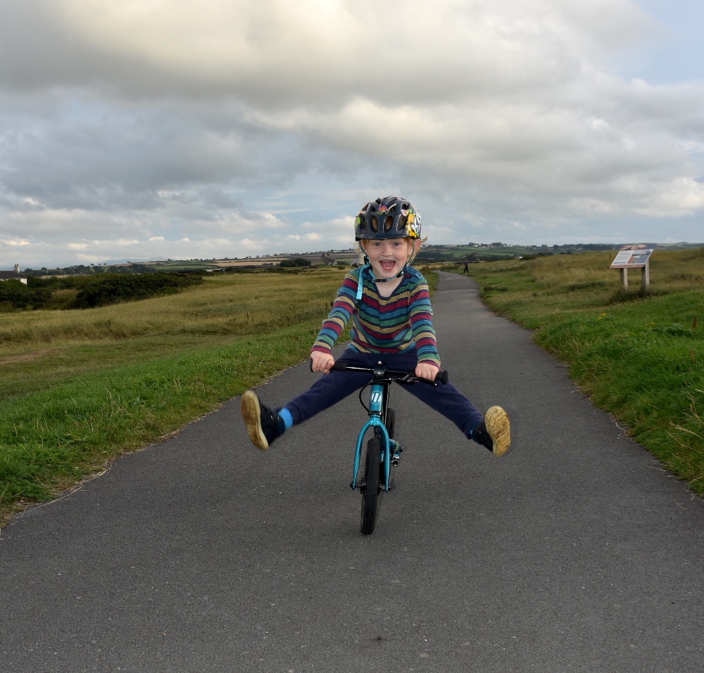 How to choose the right size kids' bike: A young boy on a balance bike with his legs in the air