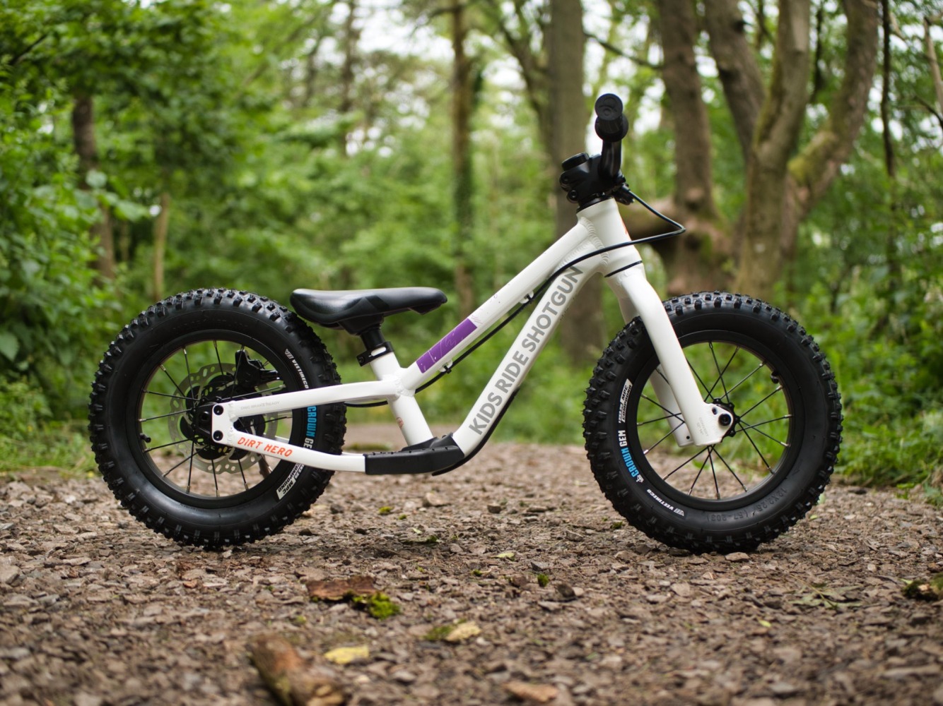 A side view of the Shotgun Dirt Hero balance bike photographed in the woods