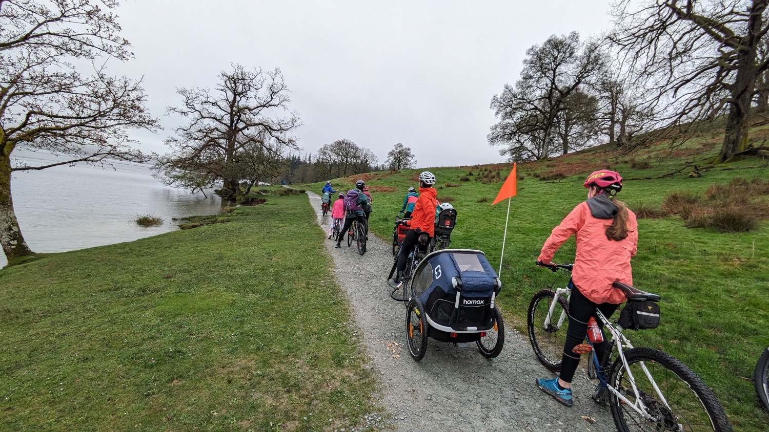 a large group of colourful cyclists riding along the shore of windermere