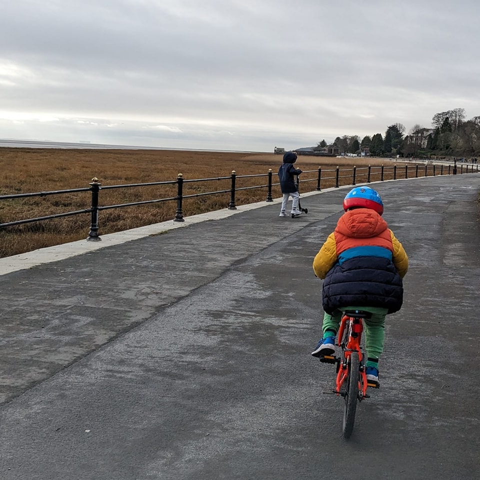 child riding an orange bike along grange prom