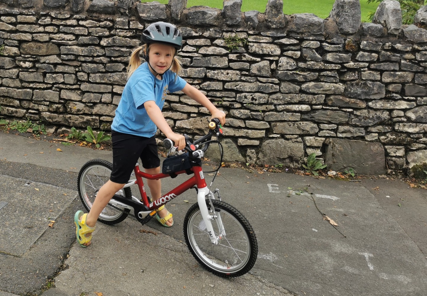 Best 16" kids' bikes: A girl standing over her 16 inch woom Automagic bike, in front of a brick wall