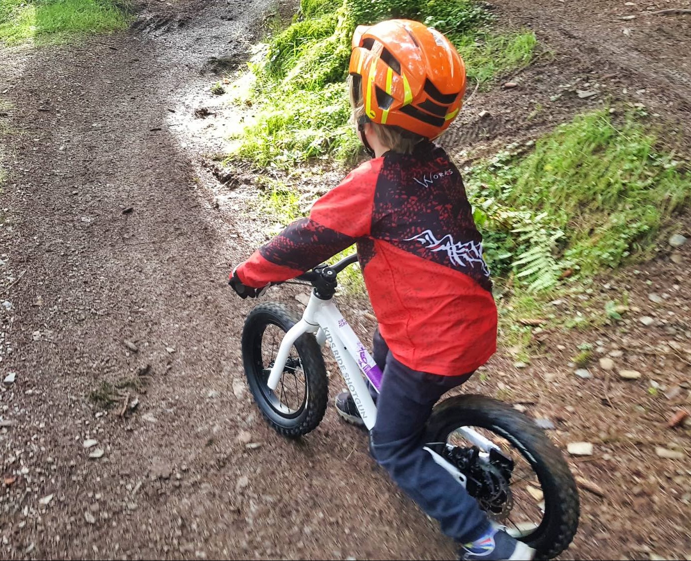Boy on the Dirt Hero balance bike on a muddy trail