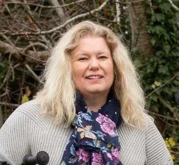 Karen Wood, co-founder of Kidvelo, pictured in front of a tree wearing a floral scarf