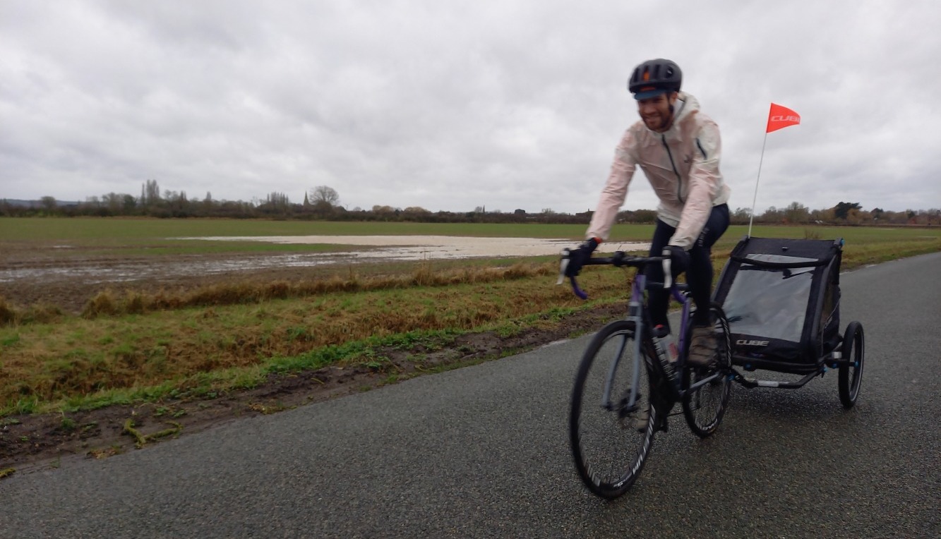 A man riding a road bike with a trailer attached to the back